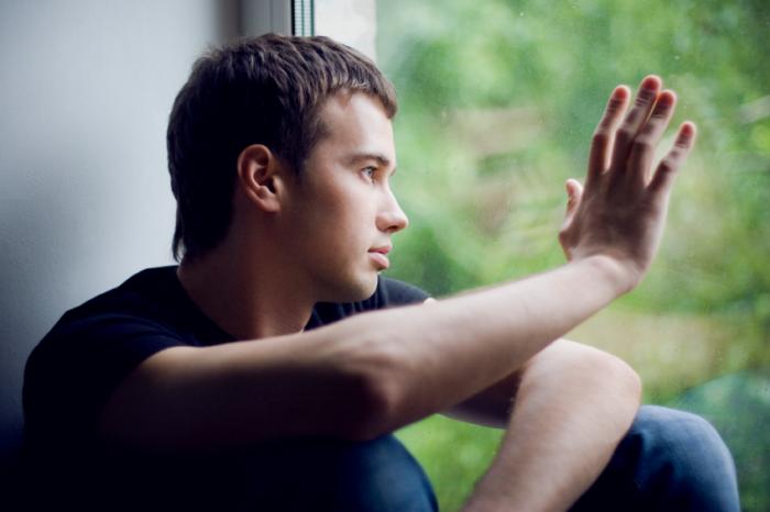 man-looking-pensively-through-window